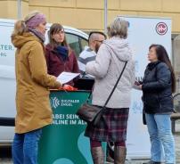 Um den Info-Stand des Digitalen Engel stehen fünf Menschen und unterhalten sich. Im Hintergrund steht das Info-Mobil sowie ein Rollup der Hillerschen Villa.