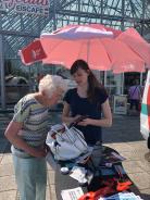 Petra zeigt einer Seniorin draußen am Infostand Dinge am Smartphone.