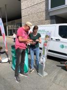 Am Info-Stand des Digitalen Engel mit dem Info-Mobil steht die Referentin gemeinsam mit einem Senior. Sie gucken gemeinsam auf ein Smartphone,