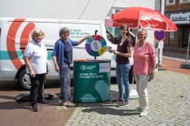 Drei Mitglieder des SeniorInnenbeirats Harsefeld stehen mit Petra am Info-Stand vor dem Info-Mobil und lächeln in die Kamera.