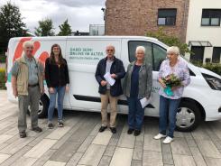 Petra steht mit drei Vertreter:innen des Jugendbeirats oder des Deutschen Roten Kreuz vor dem Info-Mobil.