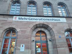 Die Fassade mit mehreren Fenstern und der Eingang des Mehrgenerationenhauses