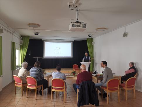 Die Teilnehmenden sitzen im Raum und blicken zur Präsentation an der Wand