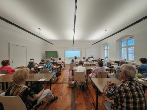 Die Teilnehmenden sitzen im Raum und schauen zur Präsentation an der Wand