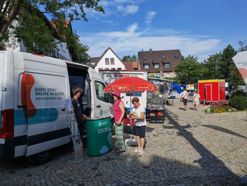 Zwei Besucherinnen stehen vor dem Infomobil und unterhalten sich mit unserem Referenten Johannes