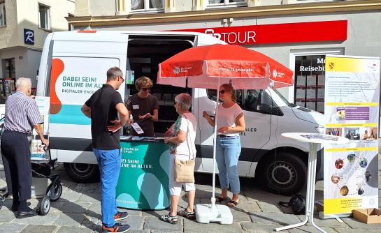 Besucher:innen stehen vor dem Infomobil und unterhalten sich mit unserem Referenten