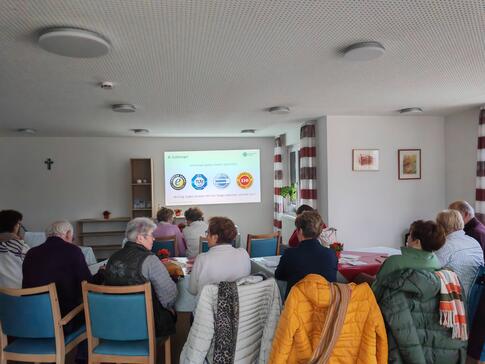 Die Teilnehmenden sitzen im Raum und schauen zur Präsentation an der Leinwand