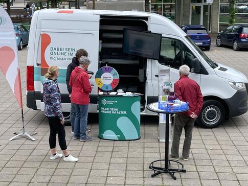 Besucher:innen stehen vor dem Infomobil und unterhalten sich mit unserem Referenten