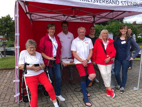 Petra (rechts) und Martina (dritte von rechts) stehen mit Ulli Baschke (vierter von rechts) mit vier Mitgliedern des SoVD vor einem Zelt.